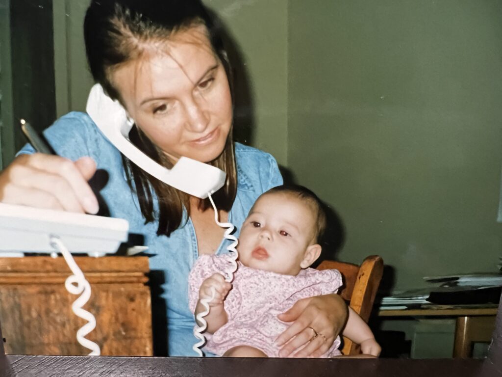 carey with her baby while holding phone trying to tidy up work