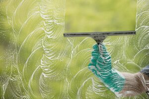 cleaning window with window cleaner making satisfying patterns with foam