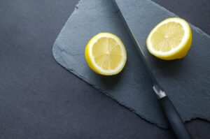 lemon split into two with a knife on a black surface